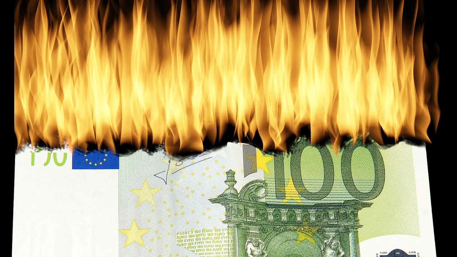 Billet de cent euros en train de brûler, hautes flammes orangées sur fond noir
