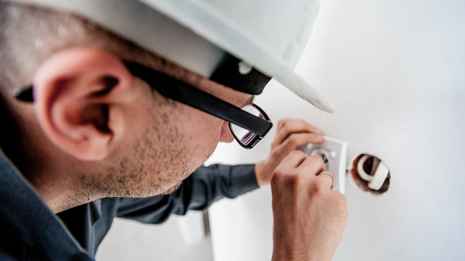 Électricien casqué installant une prise de courant murale sur un chantier