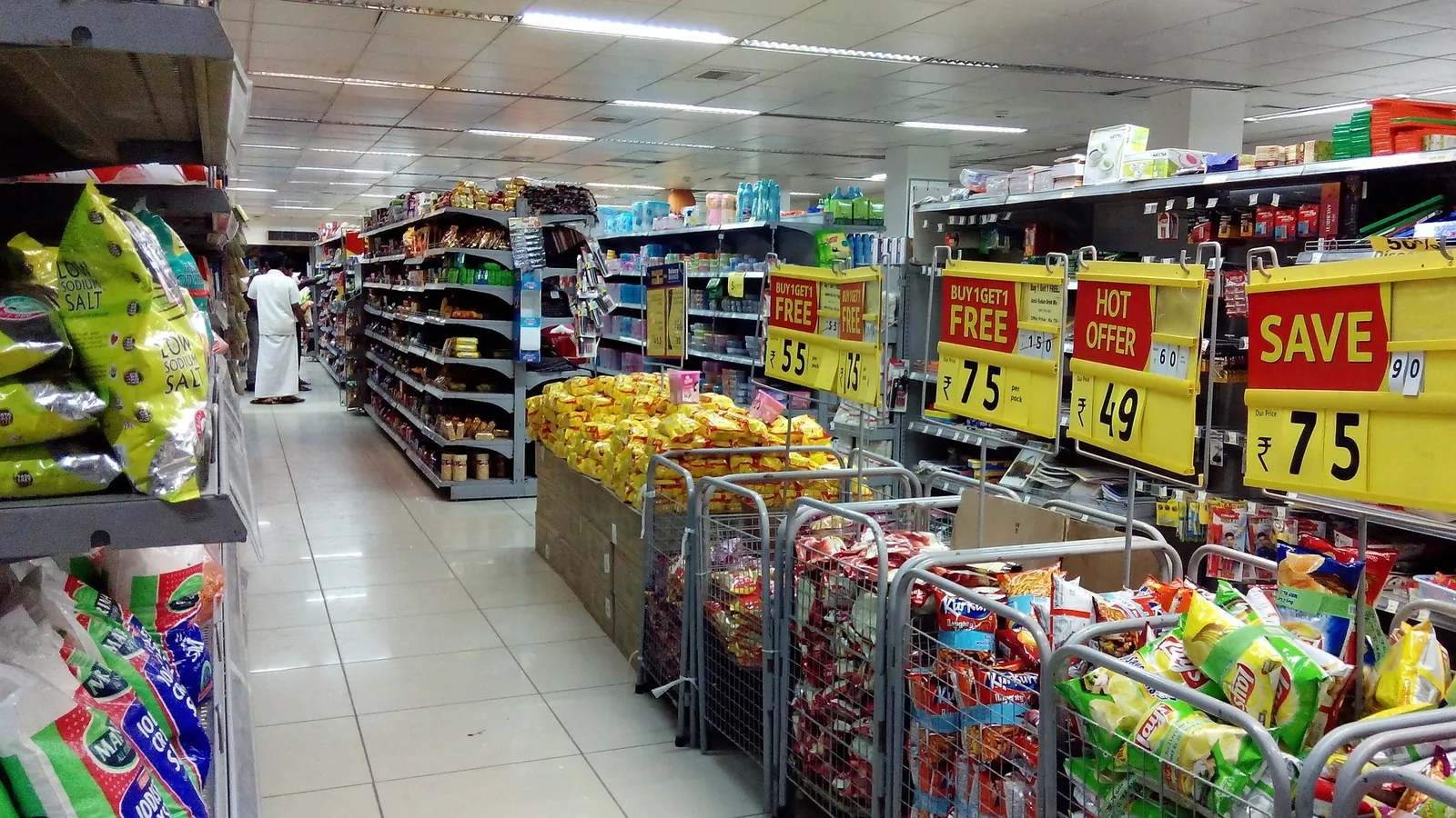 Allée de supérette bordée de rayons alimentaires et de panneaux de promotion