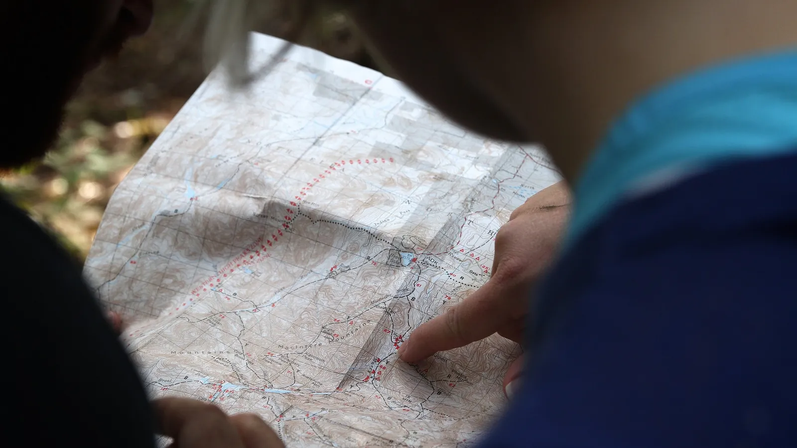 Deux personnes penchées sur une carte topographique dépliée, un doigt indique un point