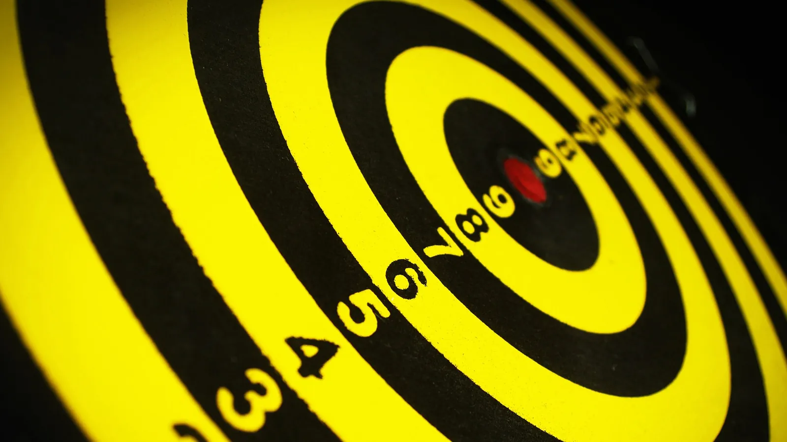 Cible de fléchettes jaune et noire vue de biais, centre rouge net au milieu