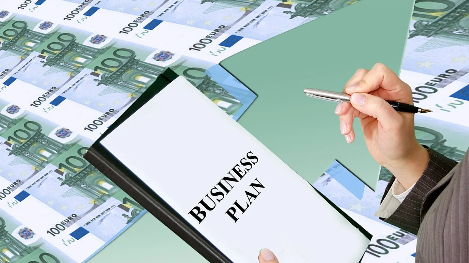 Dirigeant redigeant un business plan sur un dossier pose sur des billets de banque